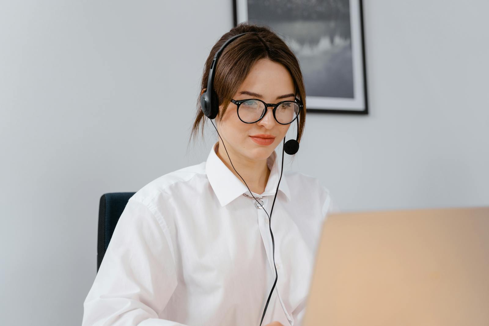 Customer support advisor wearing a headset and working on a laptop.
